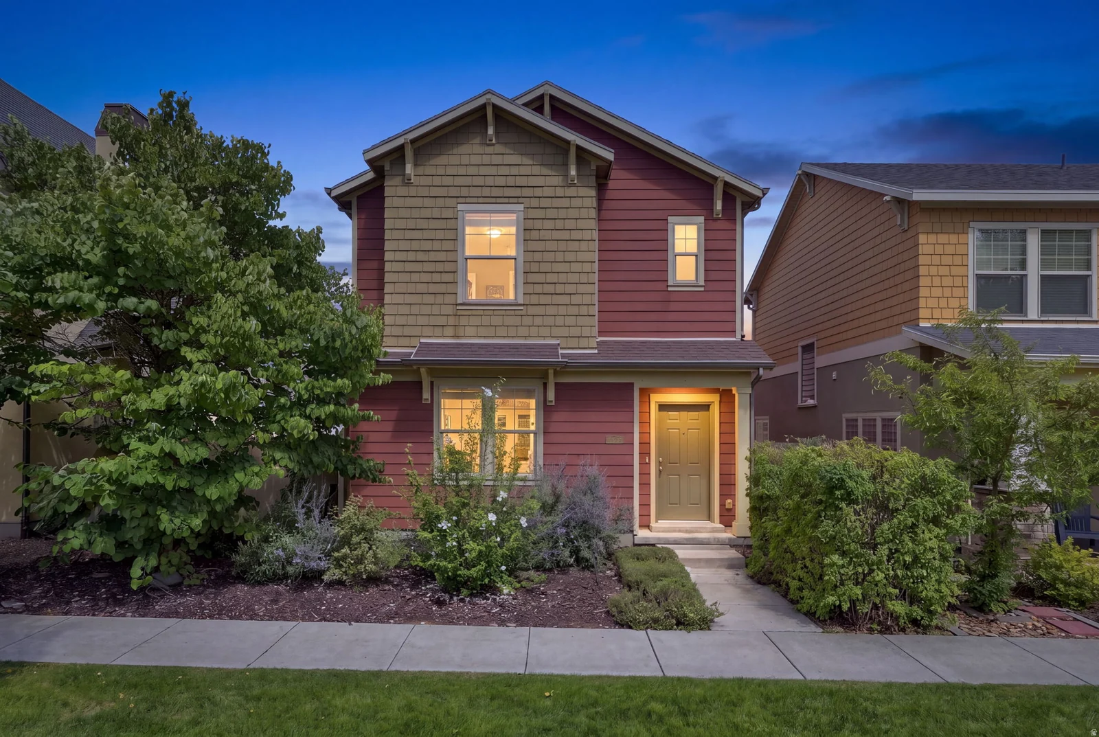 Two-story exterior with horizontal siding and shake accents, mature landscaping, and a concrete walkway